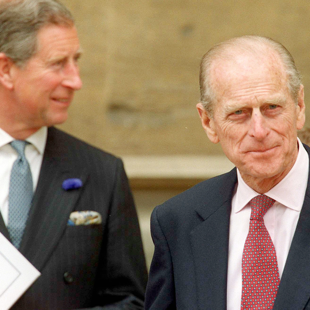 King Charles and Prince Philip pictured wearing suits and ties, with Philip smirking at the camera