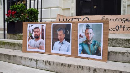 Pictures of Chi Leung Wai, Chung Biu Yuen, and Matthew Trickett, the men charged with alleged spying, are seen during a demonstration