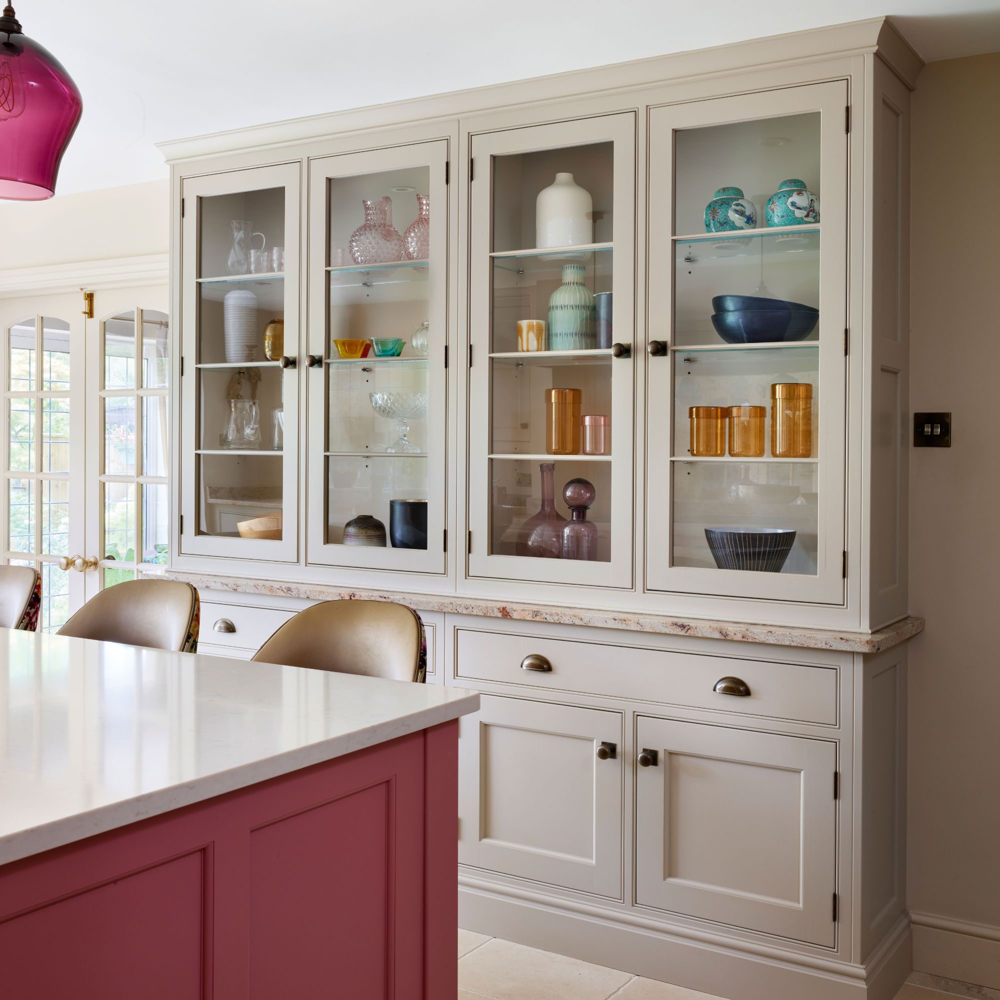 kitchen with cream cabinetry and pink island and mirrored splashback