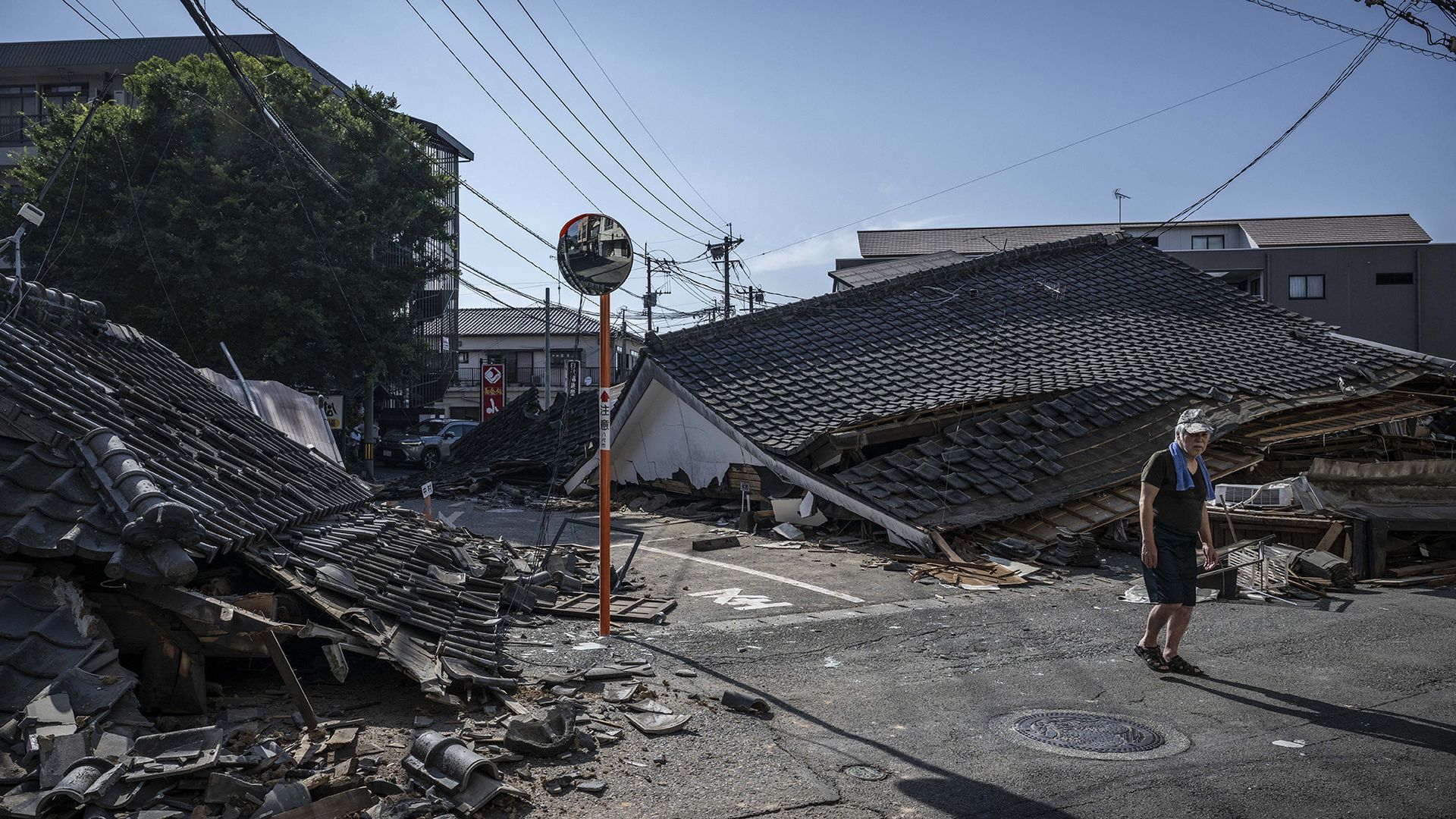 
                                A man walks past collapsed houses in Yatsushiro following a 6.8 magnitude earthquake in Kumamoto prefecture, Japan
                            