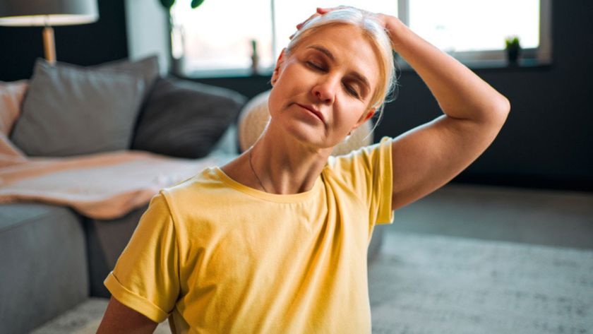 A woman wearing yellow t-short with hand over head doing neck stretch