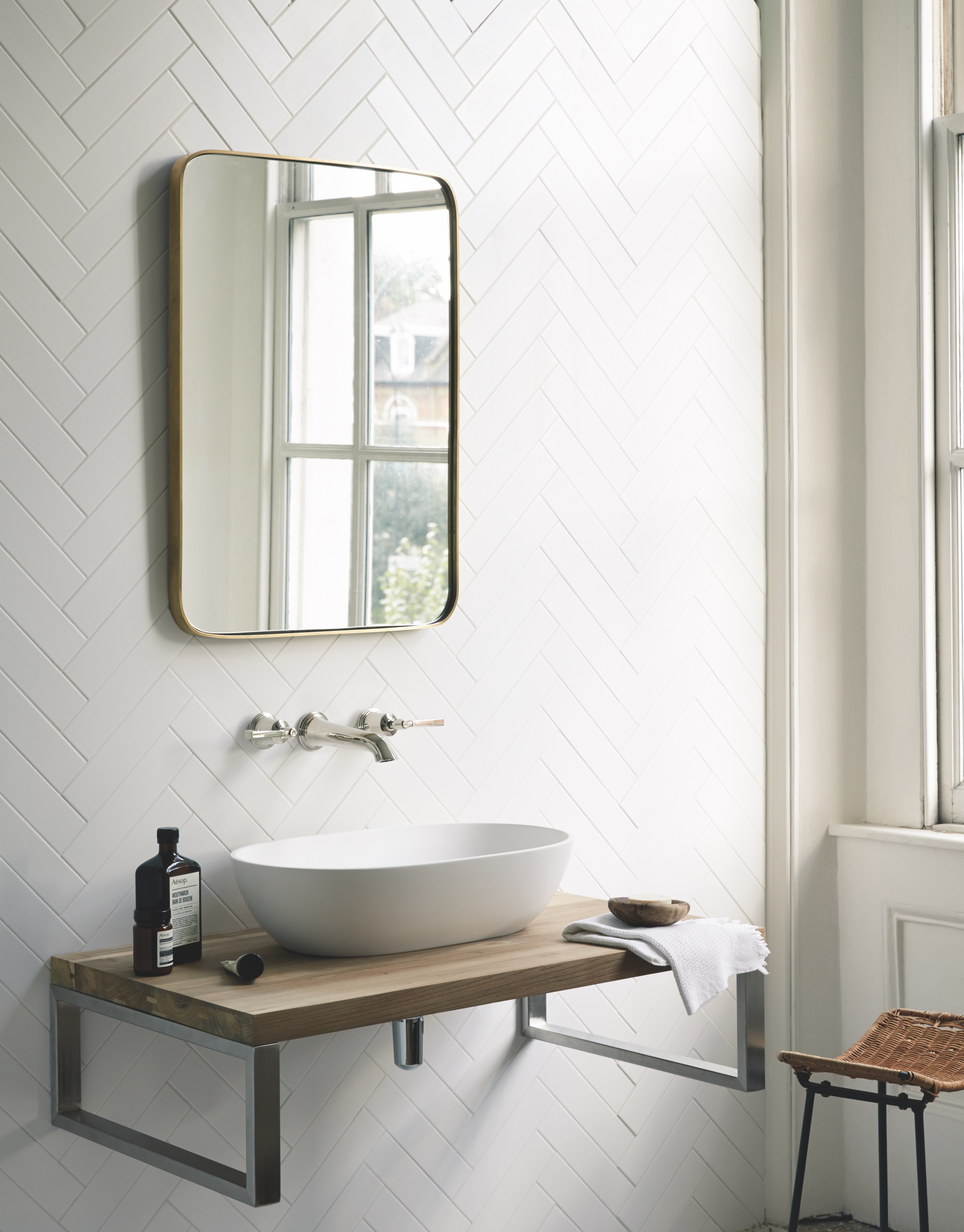 bathroom with white herringbone tiles with rounded corner mirror and freestanding sink