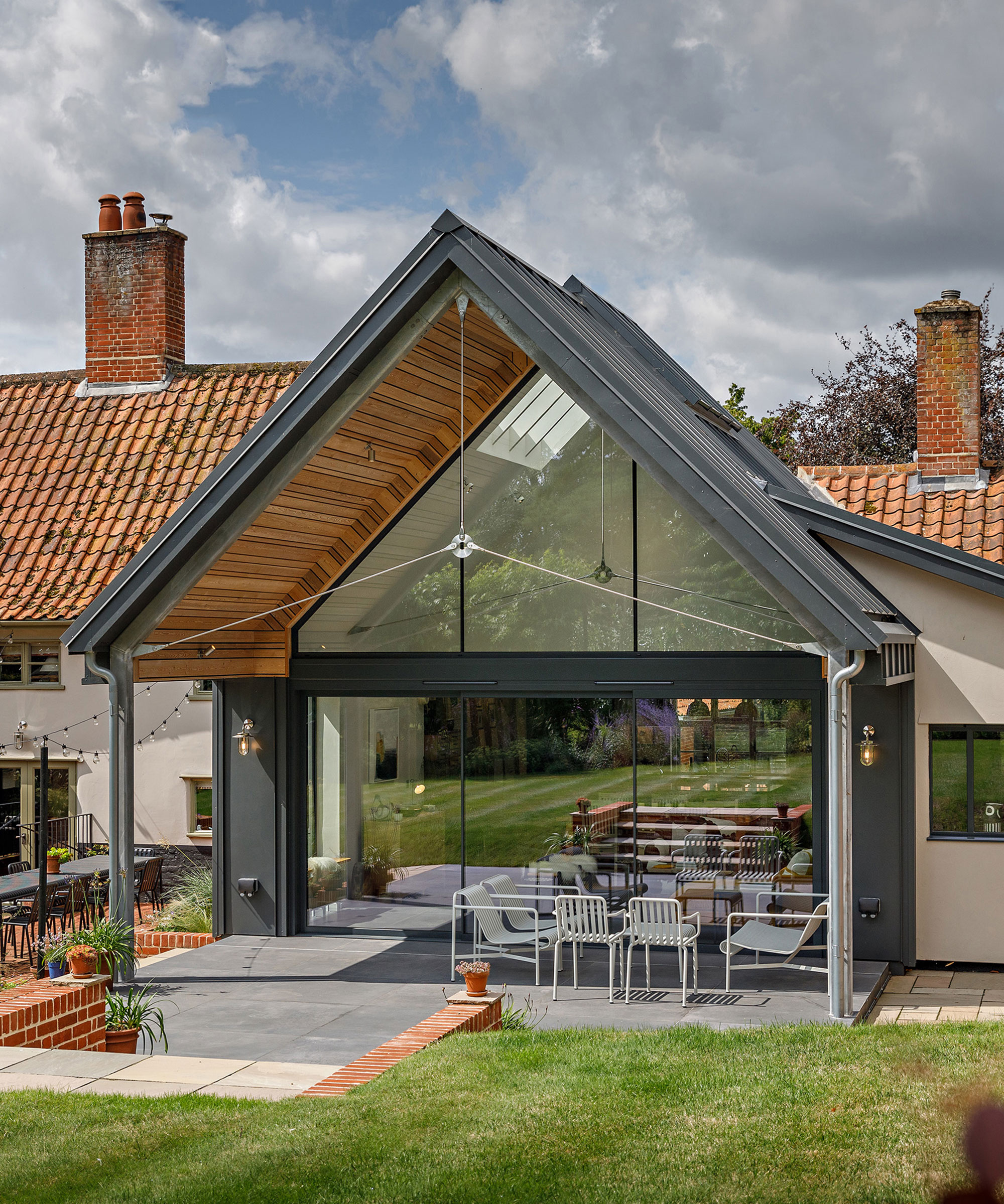 traditional cottage with a modern rear extension featuring full-height glazing and sliding doors leading out to a covered patio area