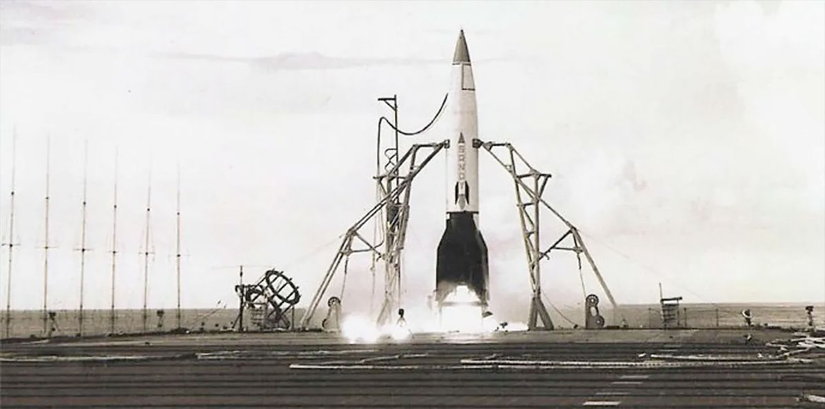 a small rocket with a white body and black fins and nose cone is prepared for launch on the fligh deck of an aircraft carrier