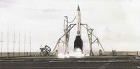 a small rocket with a white body and black fins and nose cone is prepared for launch on the fligh deck of an aircraft carrier