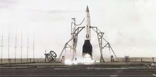 a small rocket with a white body and black fins and nose cone is prepared for launch on the fligh deck of an aircraft carrier