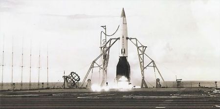 a small rocket with a white body and black fins and nose cone is prepared for launch on the fligh deck of an aircraft carrier