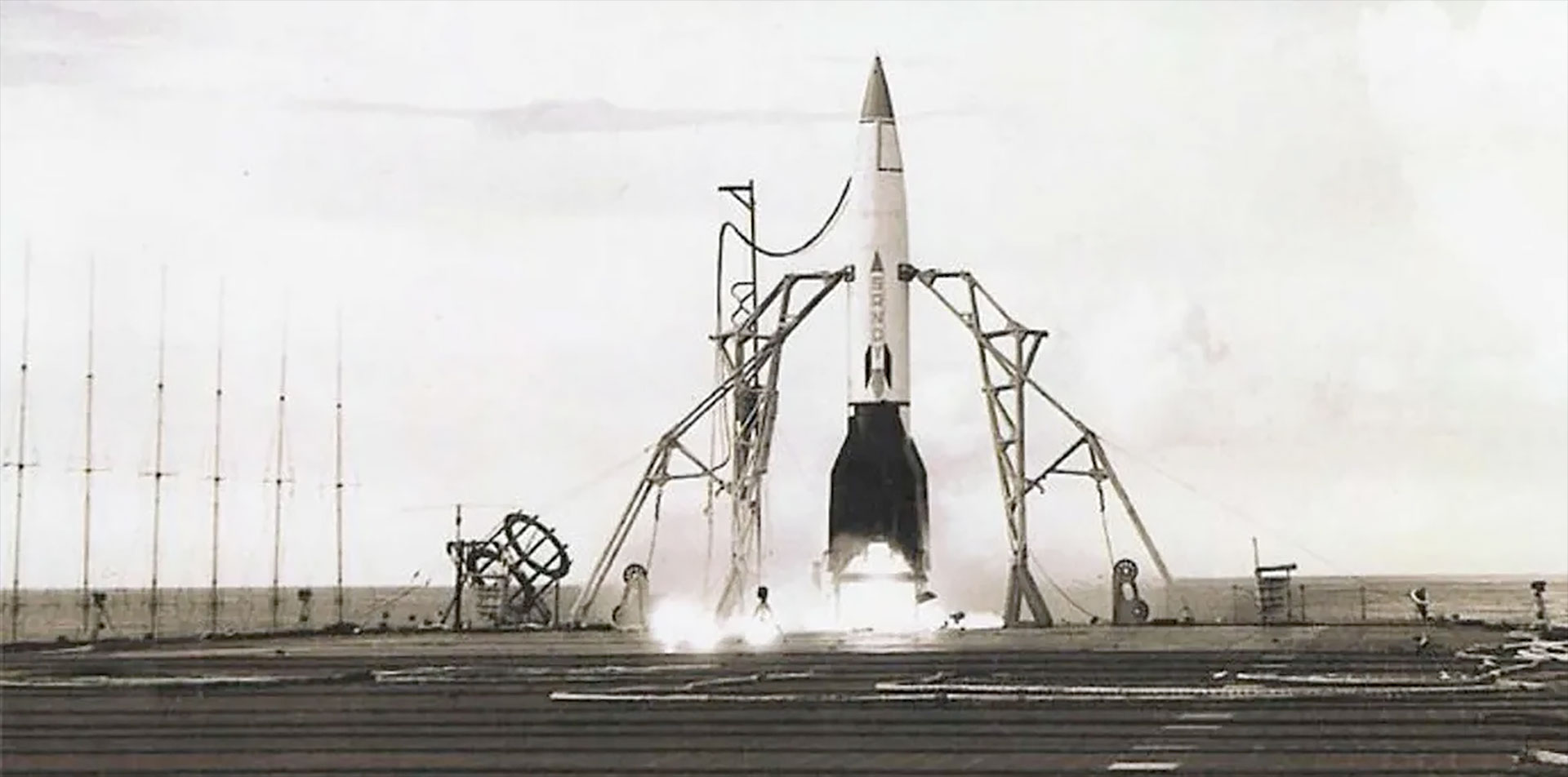 a small rocket with a white body and black fins and nose cone is prepared for launch on the fligh deck of an aircraft carrier