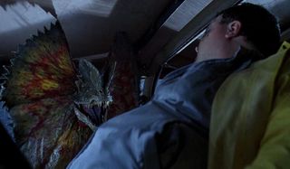 A dilophosaurus threatens Wayne Knight in Jurassic Park.
