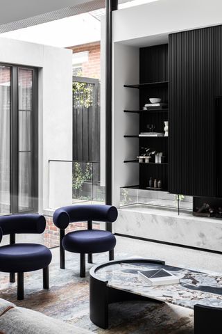 A living room with black cabinets and purple chairs