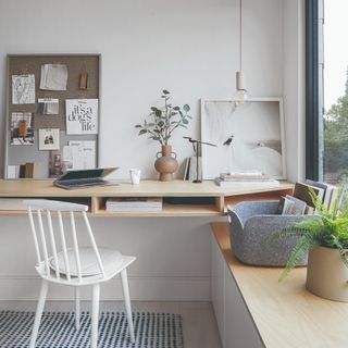 A home office with a wide table, a white chair and a pendant light