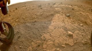 view down at cracked, rocky surface, with one wheel visible at left of image