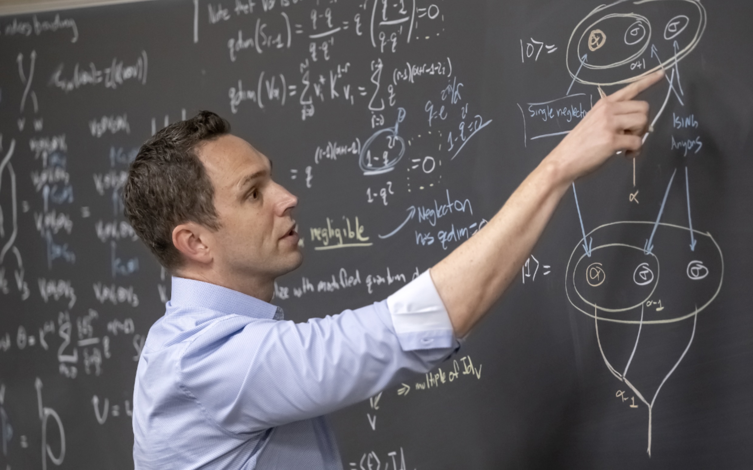 Aaron Lauda works at a chalkboard full of equations