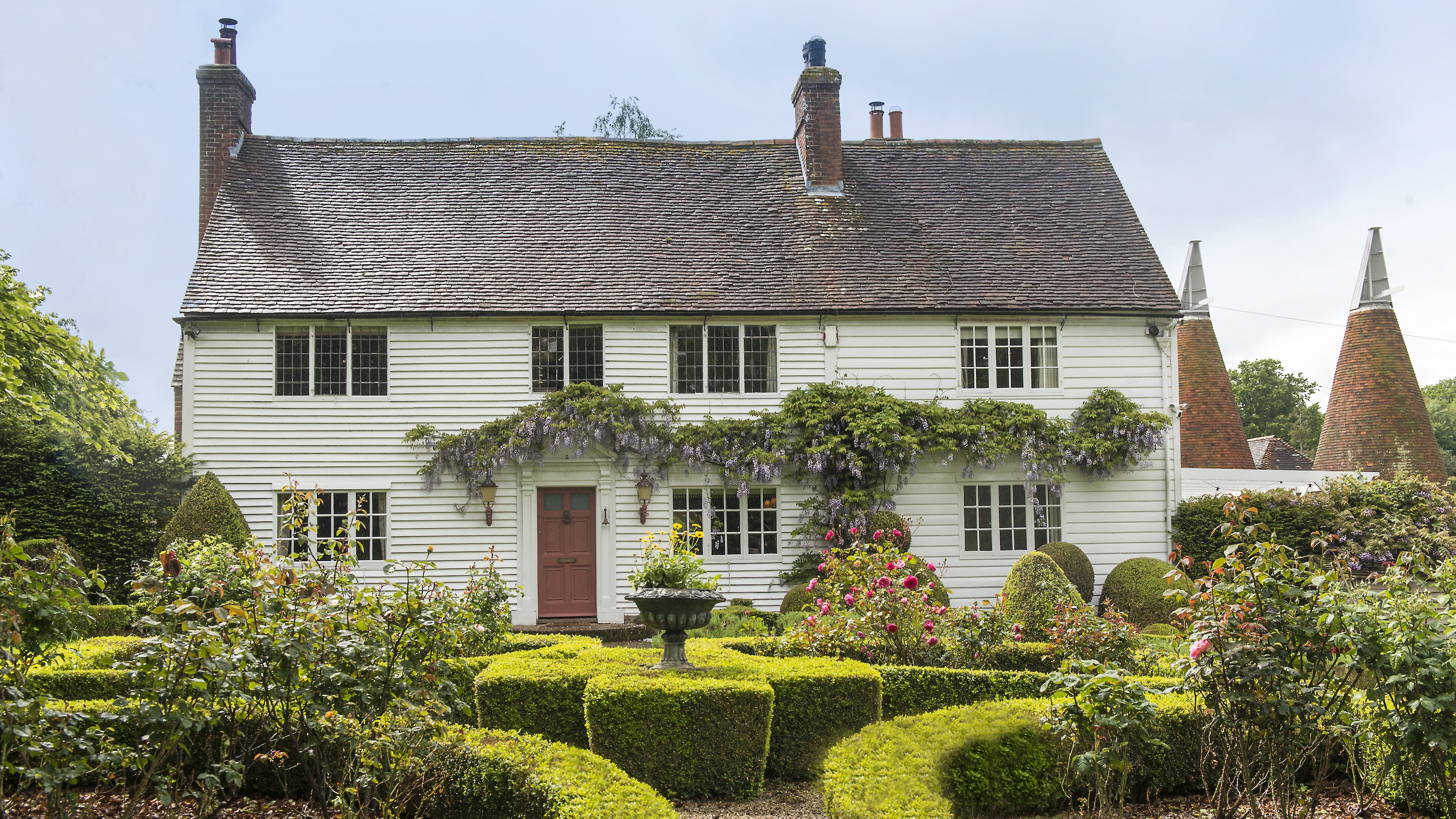 Exterior of white clapboard cottage with box hedges in front garden
