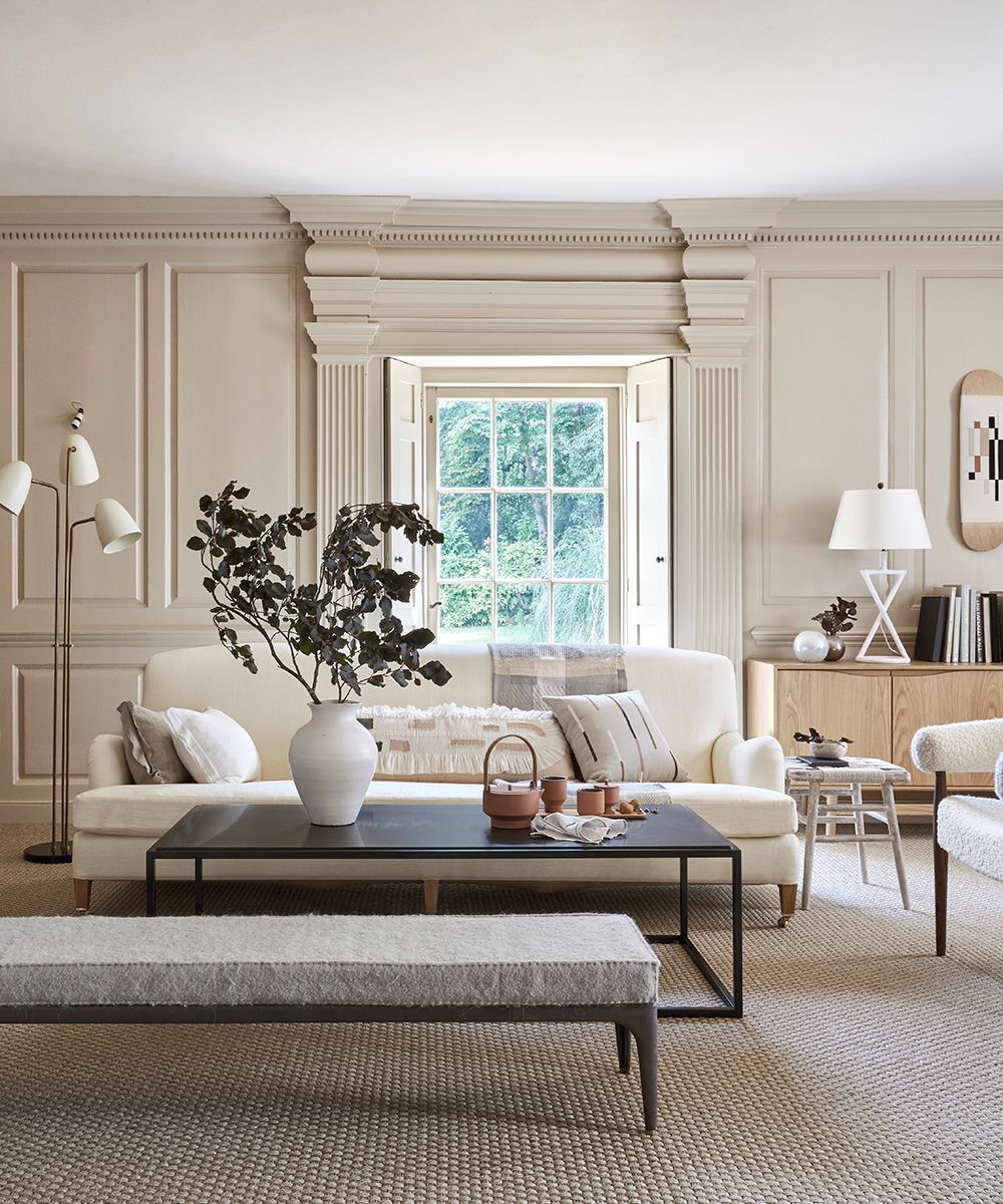 Living room pictures showing a neutral living room with panelled walls, cream sofa and black coffee table.
