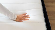 A woman's hand feels a memory foam mattress to check if it needs replacing