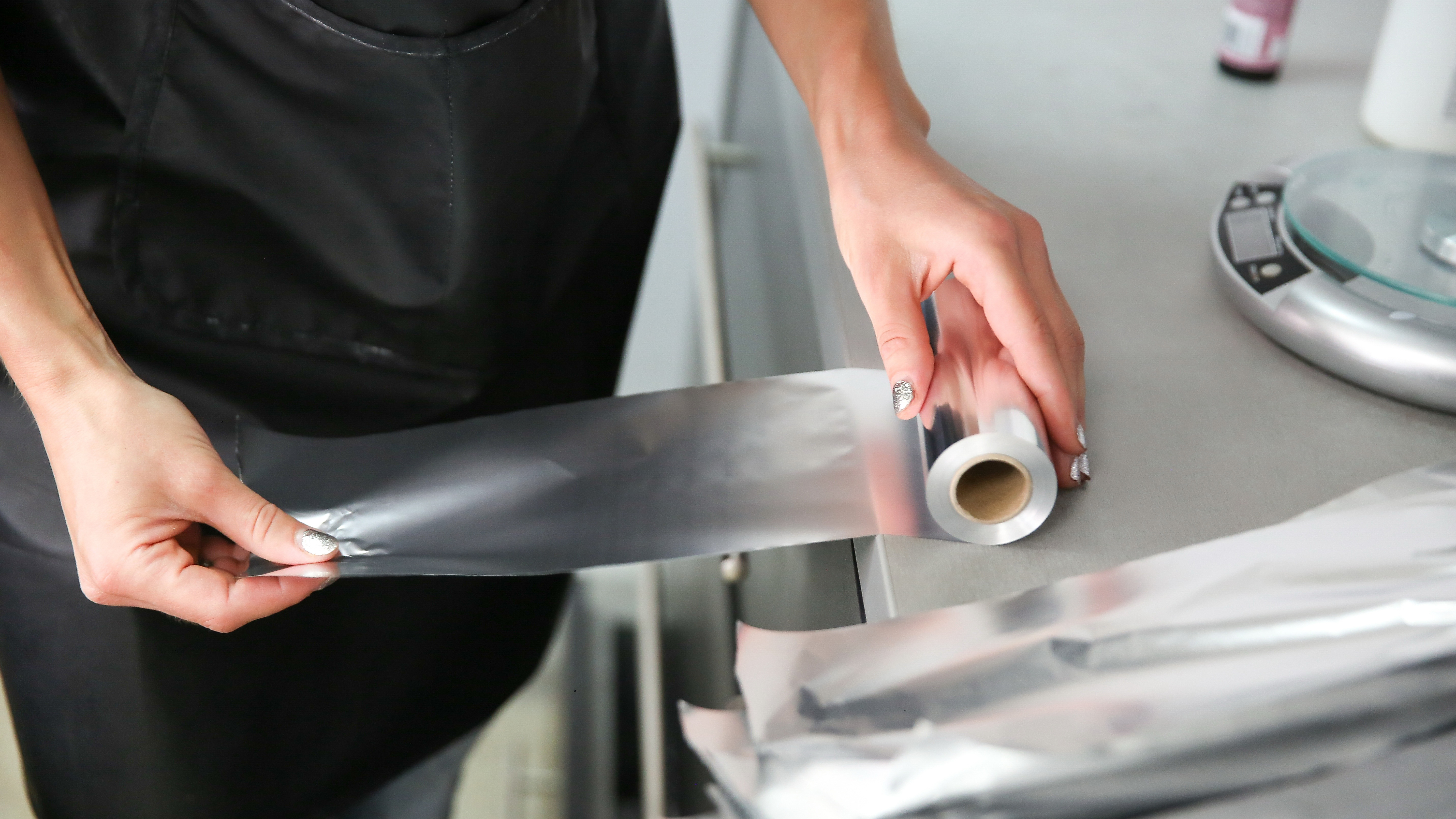 Woman tearing a sheet of aluminum foil from a roll