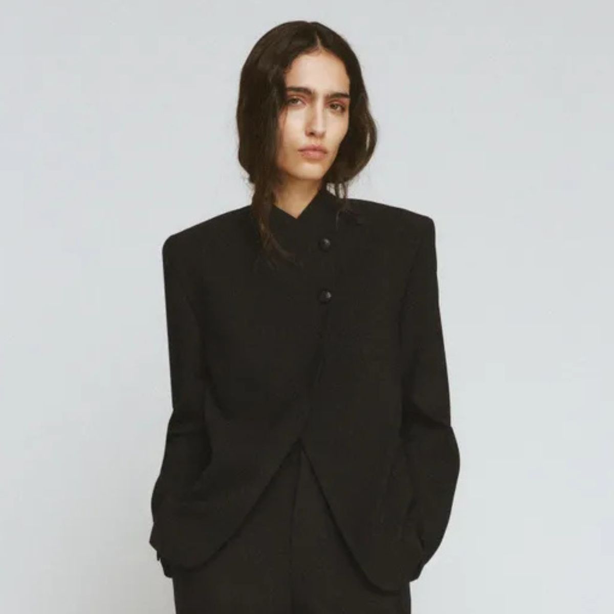 Woman wears black wrap blazer and black tailored trousers