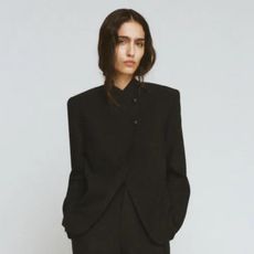 Woman wears black wrap blazer and black tailored trousers