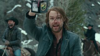 Scott Haze showing a fake badge in the snowy woods in Jurassic World Dominion.