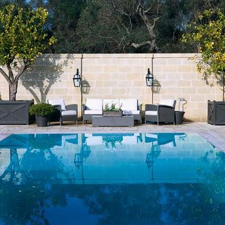 swimming pool with grey sofa and arm chair pots