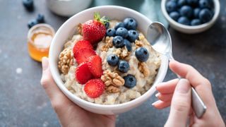 a photo of a bowl of oats topped with nuts and berries