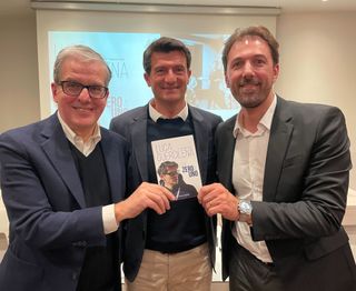 Pier Augusto Stagi, Luca Guercilena and Fabian Cancellara pose with a copy of 'Da zero a uno' at the book's launch event