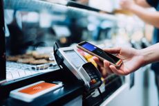 Close up of a woman's hand paying with her smartphone in a cafe