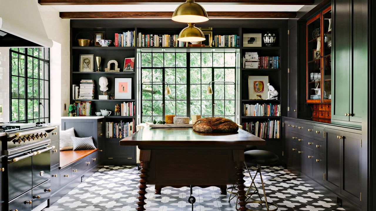 A kitchen with black and white floor tiles, black bookcases and a spanish style kitchen table with spindle legs 