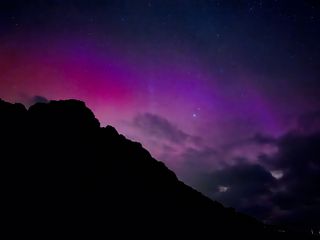 dark bklue and purple skies over a dark rocky outcrop