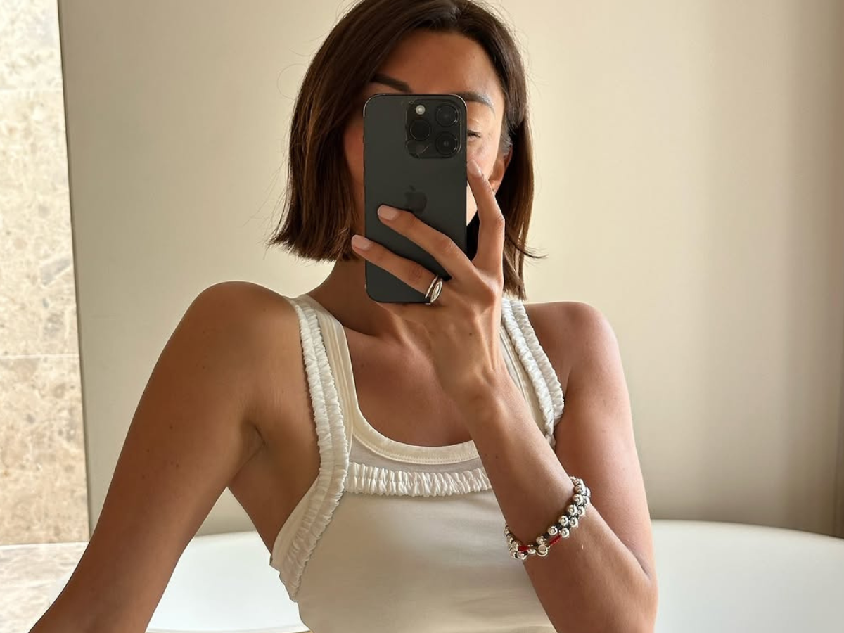 Woman wearing white tank top with ruffles.