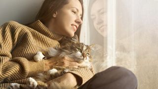 Young woman cradling Siberian cat