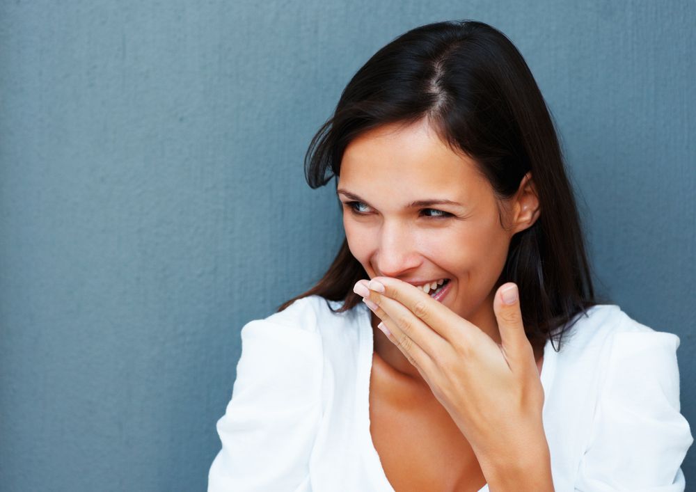 A woman giggles and covers her mouth with her hand