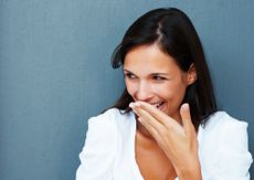 A woman giggles and covers her mouth with her hand