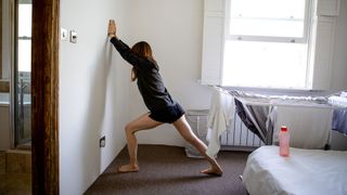 How to stretch your hamstrings: Image shows woman stretching hamstrings at home