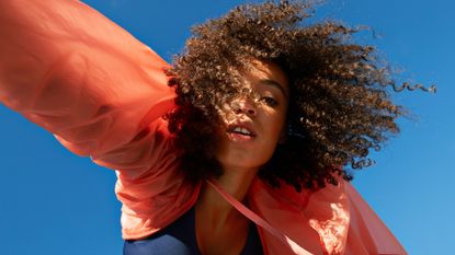 young female athlete with natural hair against clear blue sky