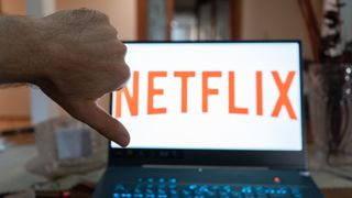 hand making thumb down in front of a laptop showing the Netflix logo