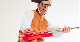 Paul Gilbert wears a tricorn hat and plays his hot-pink Ibanez signature model