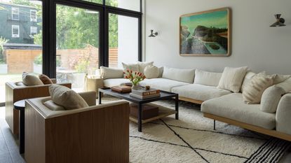 sofa arranging mistakes, neutral living room with large sectional, large rug, two armchairs, pendant, artwork, crittall doors, view of garden 