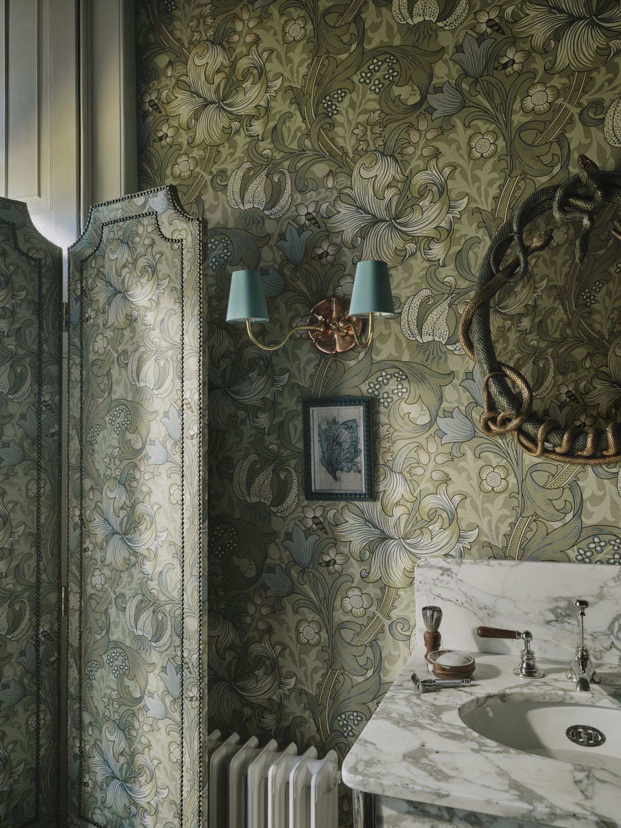 Image of a powder room drenched in a green floral patter with a marble sink.
