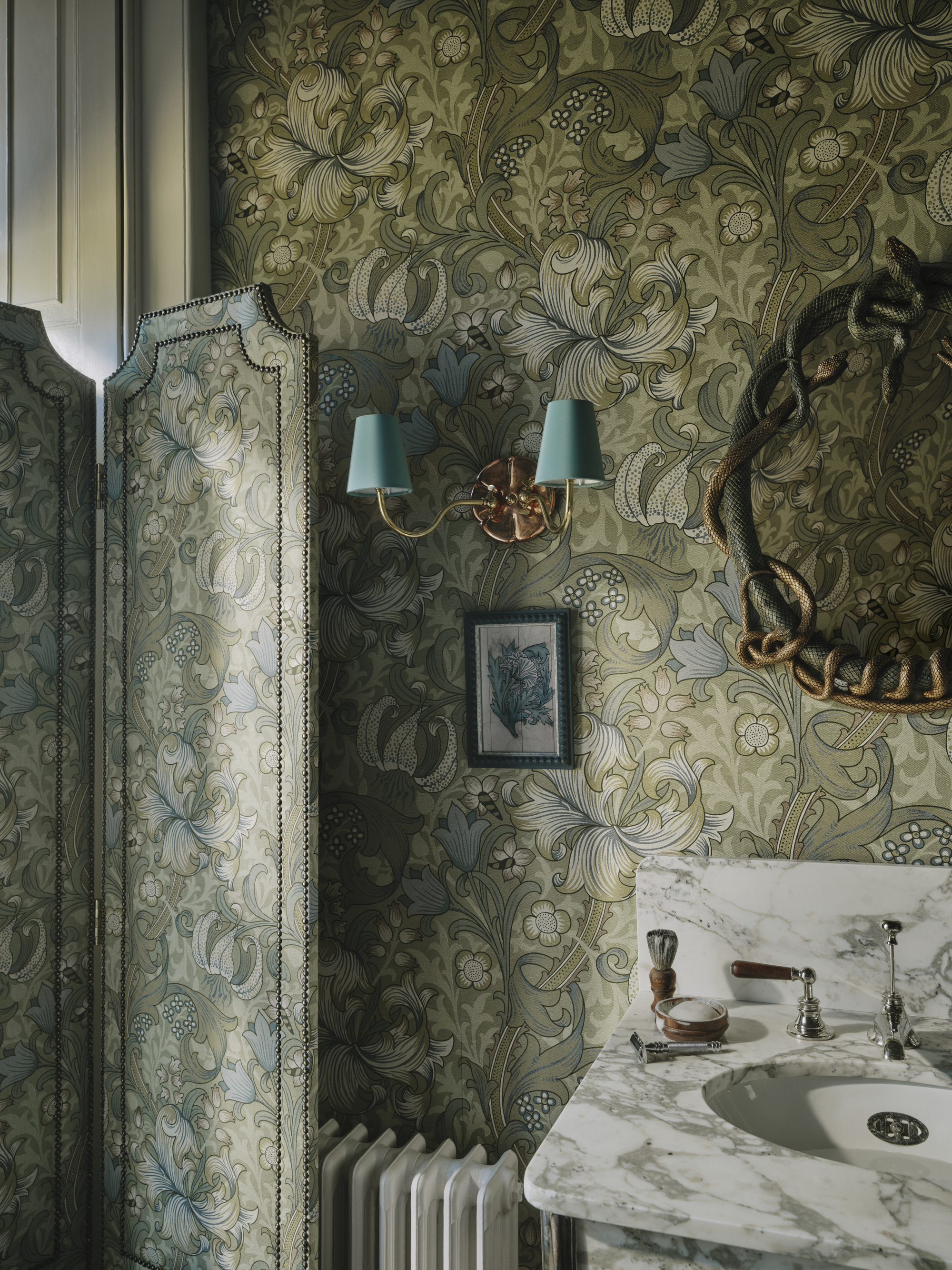 Image of a powder room drenched in a green floral patter with a marble sink.