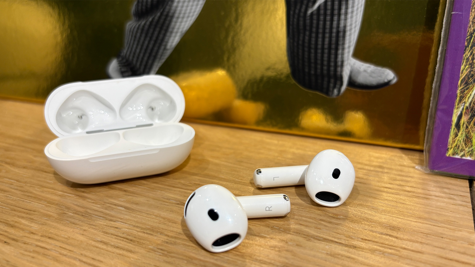 Apple AirPods 5 with Wireless Charging Case in-ear headphones on wooden shelf next to open case