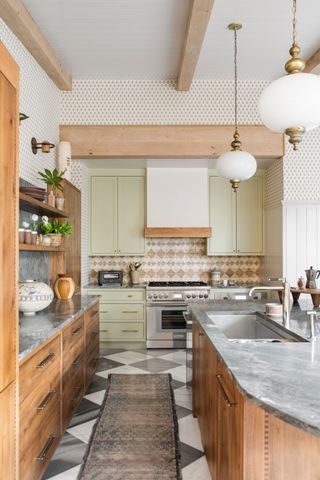 A kitchen with wooden and green cabinetry, a black and white chequered floor and a rug