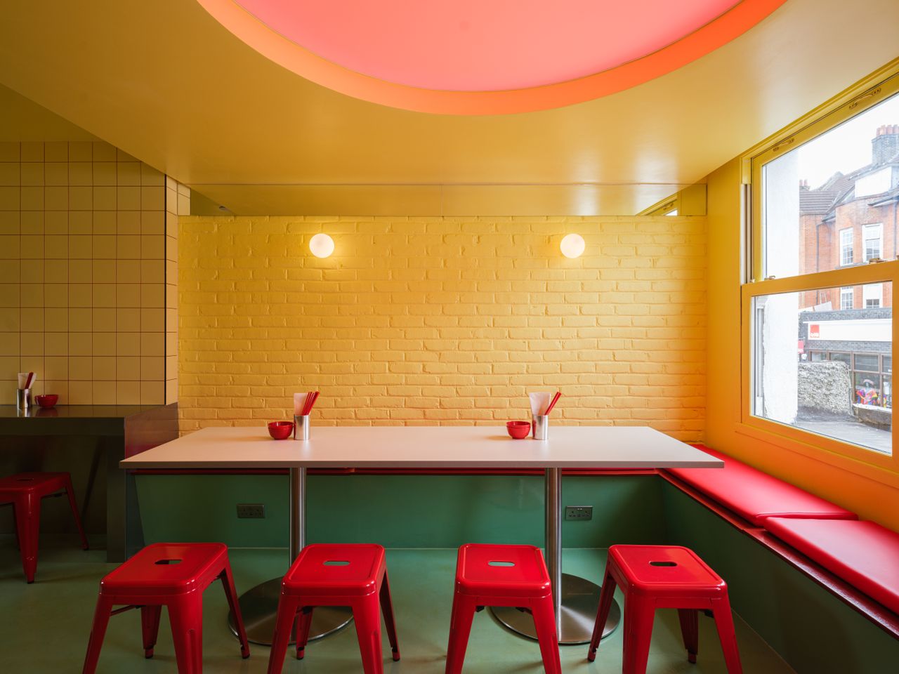A creatively designed restaurants blends buttery walls with bold accents like lacquered red chairs and floors, porthole-like ceiling lights, spherical sconces, and chrome decor.