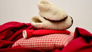 A pile of comforting objects, including slippers, a hot water bottle and a blanket