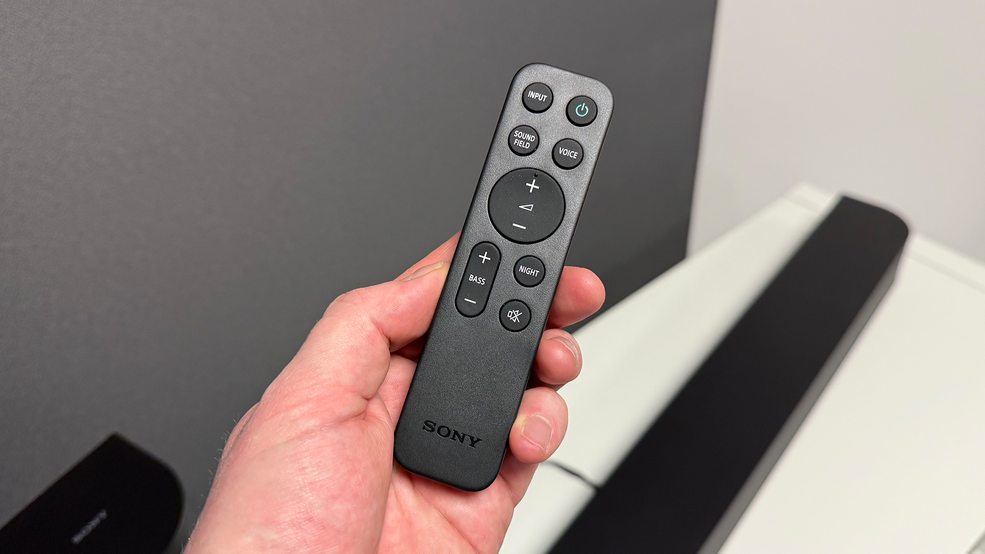 Sony Bravia Theatre System 6 soundbar remote held in hand above soundbar