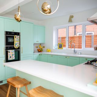 Baby blue kitchen cabinets with white countertops in G shape