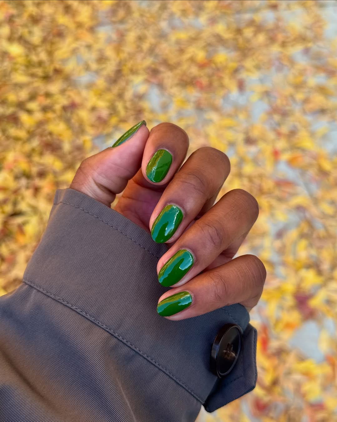 Close-up photo of a person&amp;rsquo;s hand showcasing almond nails painted green.