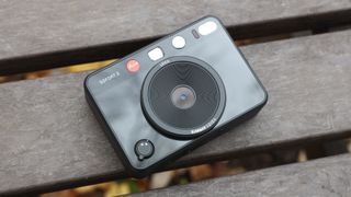 Leica Sofort 2 hybrid camera laying down on a slatted wooden table