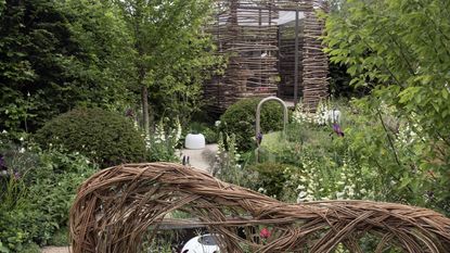 A summer garden with wicker features, trees, and white flowers at the RHS Chelsea Flower Show 2026